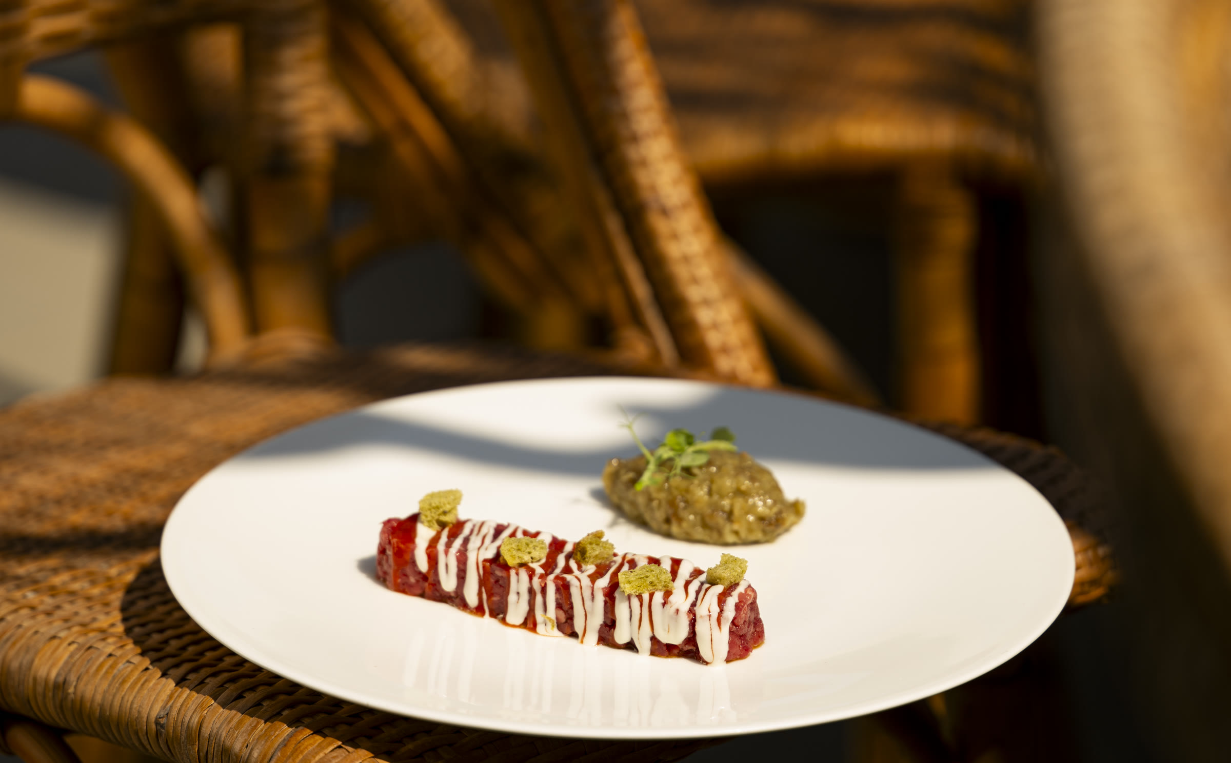 Crudo di carne servito tra le sedute in vimini della terrazza